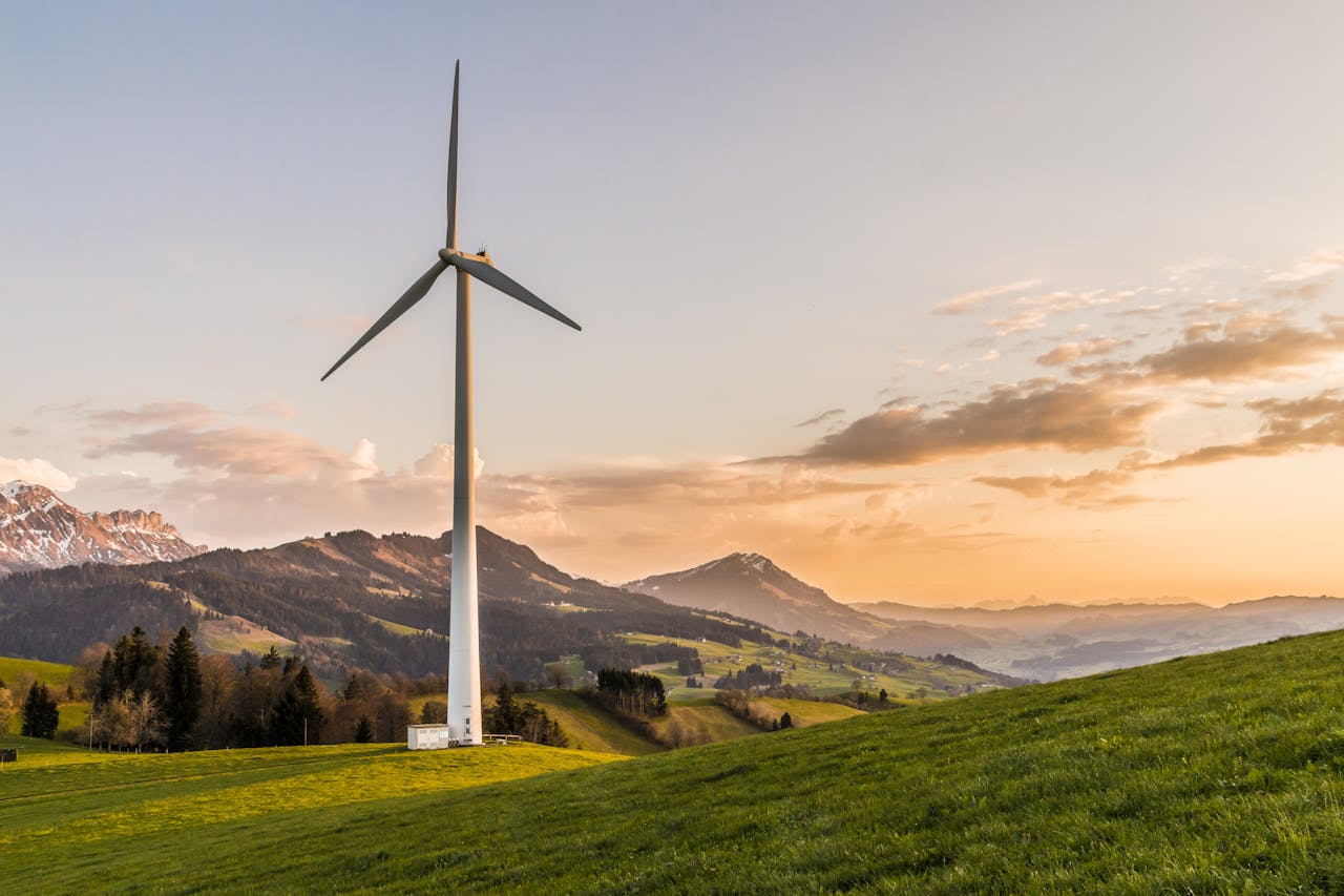 journey-02 Wind turbine amid rolling hills and mountains at sunset, symbolizing renewable energy and sustainability.